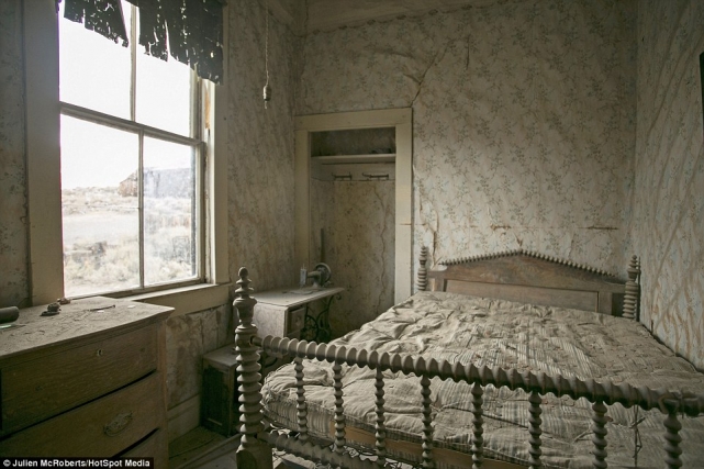 Чудом сохранившаяся спальня, в которой остался даже матрас на кровати и обои на стенах, а также швейная машинка на тумбочке